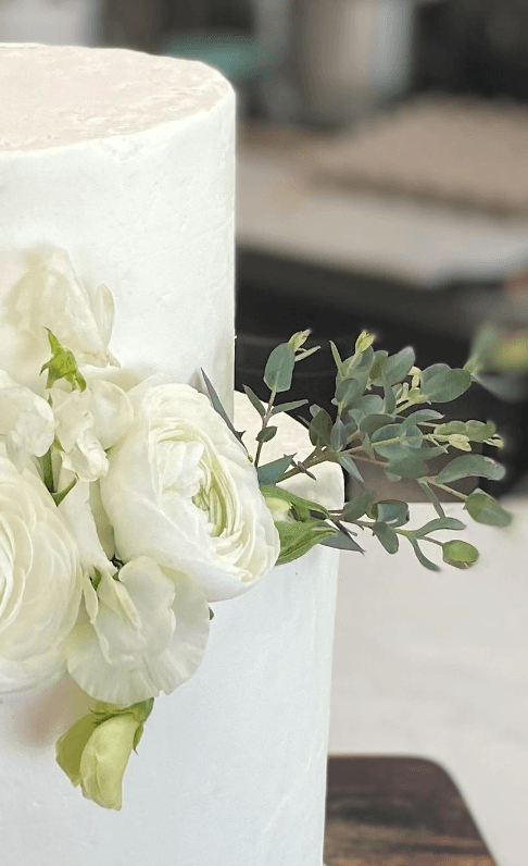 White wedding cake with ranunculus and eucalyptus — close-up detail